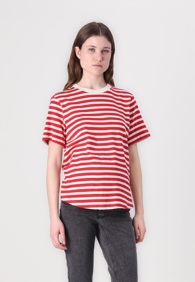 Camiseta a rayas rojas y blancas de manga corta, con cuello redondo y un corte relajado, combinada con jeans grises oscuros. Textura de algodón suave.