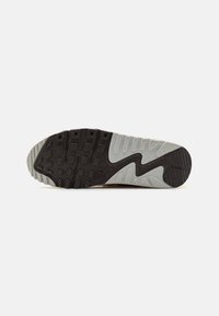 Semelle de chaussure avec des sections en caoutchouc noir et gris clair, motif texturé de la bande de roulement, et logo Nike embossé près du centre.