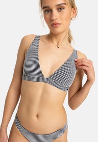 Čierno-biely gingham bikiny s hlbokým V-výstrihom a širokými ramienkami, zodpovedajúcim nízko zdvihnutým spodným dielom, vyrobené z hladkej látky.