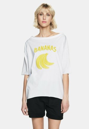 Biała, oversize'owa koszulka z napisem "BANANAS" na żółto, umieszczonym nad grafiką banana. Wykonana z miękkiej bawełny, z szerokim dekoltem i krótkimi rękawami.
