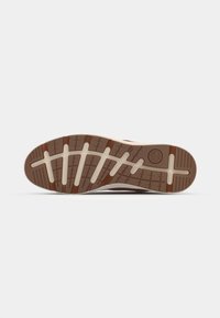 Suela de zapatilla de goma marrón con un patrón de agarre texturizado. Entresuela en beige con acentos en capas. Sin marcas visibles ni características distintivas.