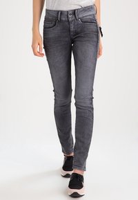 Jeans ajustados grises con una textura suave y un desvanecimiento sutil, que cuentan con un diseño de cinco bolsillos y cierre frontal con botón.