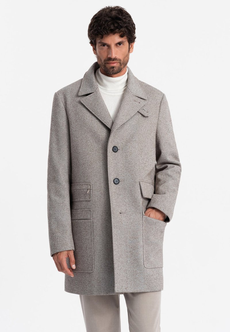 Abrigo de lana gris en diseño de espiga con cuello de muesca, dos botones y cuatro bolsillos. Costuras frontales y laterales visibles; tejido texturizado.