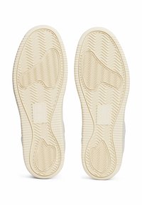 Rubberen sneakerzolen in off-white, met een gestructureerd vissengraatpatroon en verstevigde gebieden voor duurzaamheid.