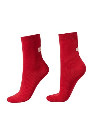 Chaussettes rayées rouges avec un léger éclat, design hauteur cheville, dotées d'une petite étiquette beige sur le côté. Matériau texturé pour le confort.