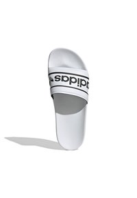 Vit halksandal med en texturerad läderliknande övre del. Har en svart märkesrem tvärs över mitten och en slät platt sula.