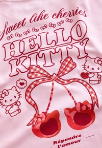 Pink fabric with red "Hello Kitty" text, two cherries shaped like Hello Kitty heads with a checkered bow, and small Hello Kitty characters.