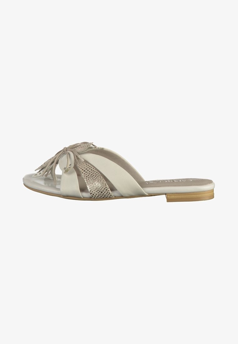 Sandale plate beige pour femme, slip-on, avec des brides croisées, détail motif serpent métallique et ornement à franges sur le dessus, petit talon en bois.