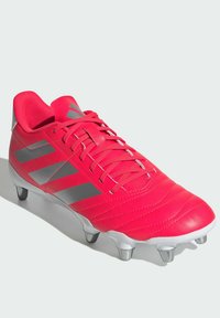 Scarpa da calcio rosa brillante con superficie texturizzata, strisce argentate e collo della caviglia imbottito. Presenta sei tacchetti metallici sulla suola.