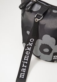 Black and gray fabric bag featuring floral patterns, dual zipper closure, and a sturdy black strap with white branding detail.