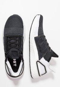 Czarno-białe sportowe buty z teksturowanym wierzchem z dzianiny, z amortyzowaną podeszwą, z zapięciem na sznurówki oraz akcentującymi szczegółami na pięcie.