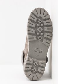 Suela de bota de ante gris con suela rugosa, marca "Tommy Jeans", y talla 37 visible sobre un fondo blanco.