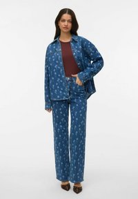 Denim-takki ja housut sinisellä kukkakuvioilla. Takki on yläosastaan väljää mallia ja siinä on napit; housut ovat leveälahkeiset, molemmat pehmeästä materiaalista.