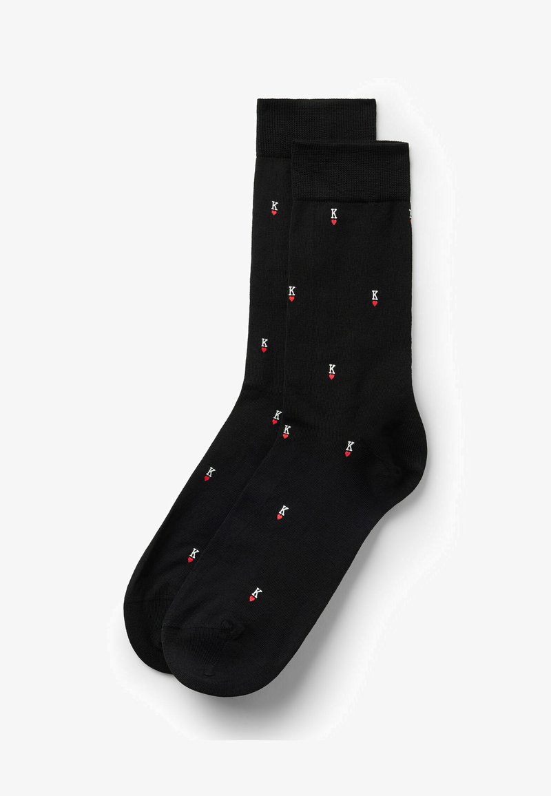 Chaussettes noires pour homme ornées de petits « K » blancs au-dessus de symboles de cœur rouges, répartis de manière uniforme.