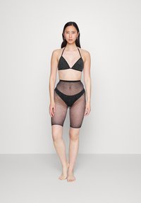Top de bikini preto e brilhante com copas triangulares e alças para o pescoço; calções de malha de cintura alta, até ao joelho, coordenados, com um padrão texturizado.