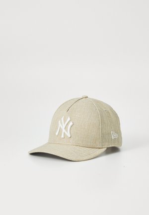 Cappellino da baseball beige con tessuto testurizzato, logo ricamato bianco e visiera curvata. Presenta una forma strutturata e un design a sei pannelli.