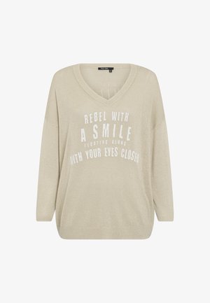 Beige sweater with a V-neck design, long sleeves, made of a textured, shimmery fabric. Features white printed text in a bold font.