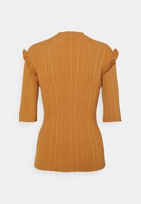 Haut côtelé de couleur moutarde avec des manches trois-quarts. Présente des accents froncés sur les épaules et un col haut.