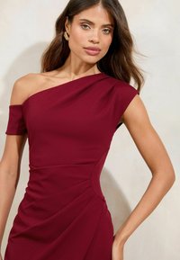 Rochie burgundy cu un umăr, cu mânecă scurtă, design pliat și textură netedă. Prezintă un corset ajustat și detalii drapate.