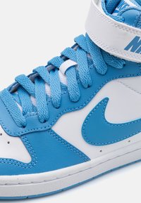 High-top sneaker with blue leather upper, white accents, padded collar, and blue laces. Features a prominent swoosh logo and textured tongue.