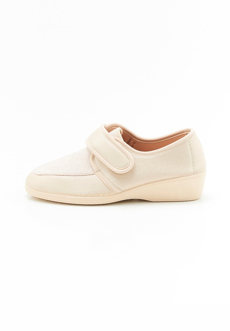 Scarpa in tessuto beige con cinturino in velcro, punta tonda e superficie testurizzata. Suola a zeppa bassa per una leggera elevazione.