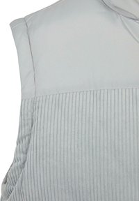 Chaleco sin mangas de color gris claro que presenta un panel superior liso y una sección inferior acanalada, confeccionado con una tela suave y con un sutil brillo.