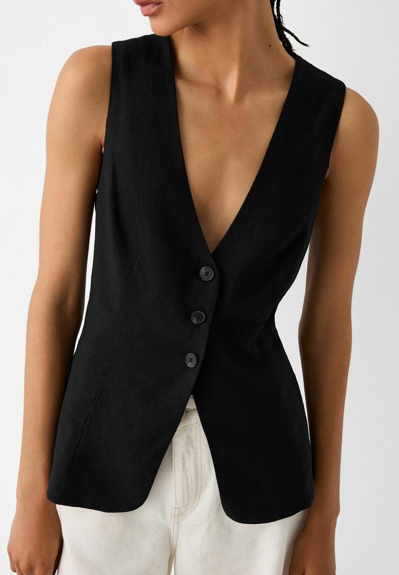 Czarna lniana kamizelka z głębokim dekoltem w kształcie V, dopasowanym krojem i czterema guzikami. Gładka tekstura, bez wzorów ani dodatków.