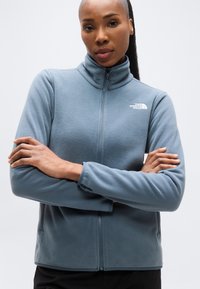 Μπουφάν φλις σε ανοιχτό μπλε, με ψηλό γιακά, ολόκληρο φερμουάρ και λογότυπο στο αριστερό στήθος. Απαλή υφή με πλαϊνές τσέπες.