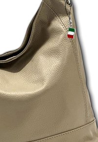 Beige lederen schoudertas met een zachte textuur, voorzien van een subtiele glans en een charm van de Italiaanse vlag.