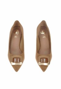 Tacchi alti in suede beige con punta affusolata, caratterizzati da accenti marroni lucidi e un dettaglio decorativo dorato sulla punta.