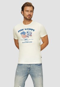 Crème-kleurig t-shirt met een grafisch ontwerp van "FISH 'n CHIPS", met een illustratie van vis en frietjes. Casual pasvorm, ronde hals, korte mouwen.