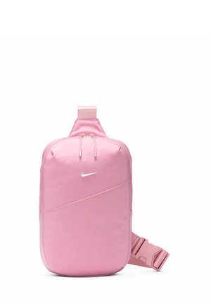 Compacte roze schoudertas met Nike-logo, dubbele ritssluiting en verstelbare band met zijgesp op een witte achtergrond.
