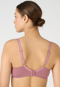 Bra senza fili rosa con spalline regolabili, chiusura a gancio, texture liscia e dettagli in metallo circolari, mostrato da dietro.