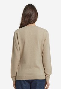 Beige tröja med långa ärmar, rundad halsringning och ribbat avslut. Mjuk textur med en slät yta, designad för en avslappnad passform.