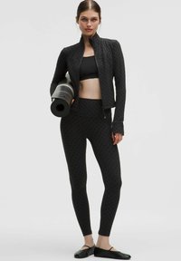 Fekete aktív sportruha szett, amely tartalmaz egy cipzáras kabátot pontozott mintával, egy szabott crop topot és magas derekú leggingset. Jóga matrac is tartozik hozzá.