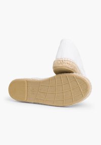 Valge lõuendist espadrillid, millel on punutud jute äär ja tekstureeritud kummist tallad. Jalapadi näitab suurust "37" ja "Valmistatud Hispaanias" templit.