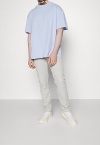 Ljusblå oversized t-shirt i bomull med rund hals, kombinerad med ljusbeige slim-fit jeans och vita plattformssneakers med snörning.