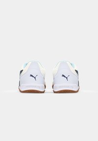 White athletic shoes with light blue accents, textured rubber soles, and a dark blue logo. Features a sleek, streamlined design.