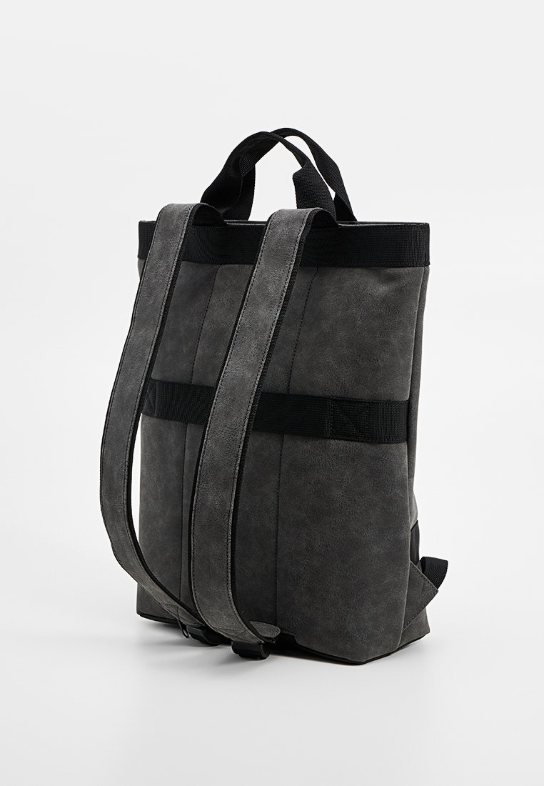 Zaino in ecopelle grigia con spallacci in tessuto nero e design strutturato. Presenta una finitura elegante e uno stile minimalista.
