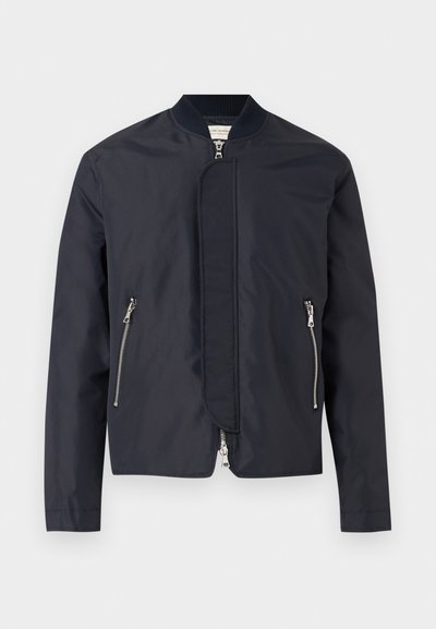 Μπουφάν τύπου bomber στο χρώμα του ναυτικού μπλε με ριμπ γιακά, εμπρόσθιο φερμουάρ καλυμμένο από φλάπ, και δύο πλαϊνές τσέπες με φερμουάρ.