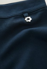 Navy blue stretch fabric with a smooth texture featuring a silver flower-shaped hardware accent near the waistband.