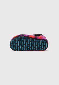 Pantofole pelose con motivo a quadri rosso, viola e nero, interno nero e suola nera con il testo "crocs" blu ripetuto.