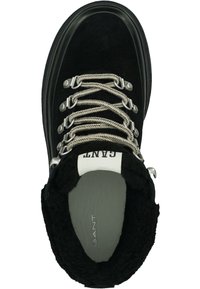 Schwarzer winterlicher Stiefel mit dicken weißen und schwarzen Schnürsenkeln, Metallösen und Fleece-Futter, von oben betrachtet.