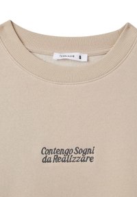 Felpa beige con collo a costine, caratterizzata da testo ricamato in blu "Contengo Sogni da Realizzare" sul davanti. Tessuto morbido, design casual.