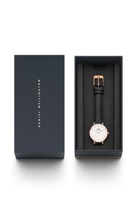 Round watch with a white face, rose gold accents, and a black leather strap, displayed in a navy blue box with a soft foam interior.