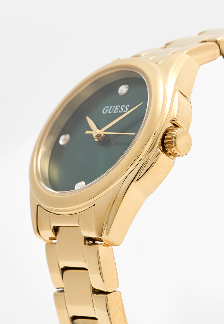 Montre en métal doré avec un cadran vert, quatre index en cristal, et un bracelet doré. Dotée d'une couronne sur le côté pour les réglages.