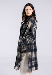 Manteau en laine à carreaux dans des tons de gris foncé, beige et marine, avec une coupe décontractée, des manches surdimensionnées et des poches latérales. Design à l'avant ouvert.