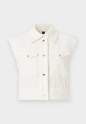 Gilet sans manches texturé blanc avec large col, boutons-pression métalliques sur le devant, et deux poches poitrine à rabat avec boutons-pression métalliques.