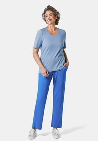 Lichtblauw T-shirt met korte mouwen en een ronde hals, gecombineerd met felblauwe, rechte broek. Beide gemaakt van een gladde stof.