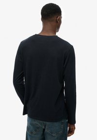 Marineblauw langshirt van katoen, met een ronde halslijn, een relaxed fit en zijsplitten aan de zoom, gecombineerd met denim jeans.